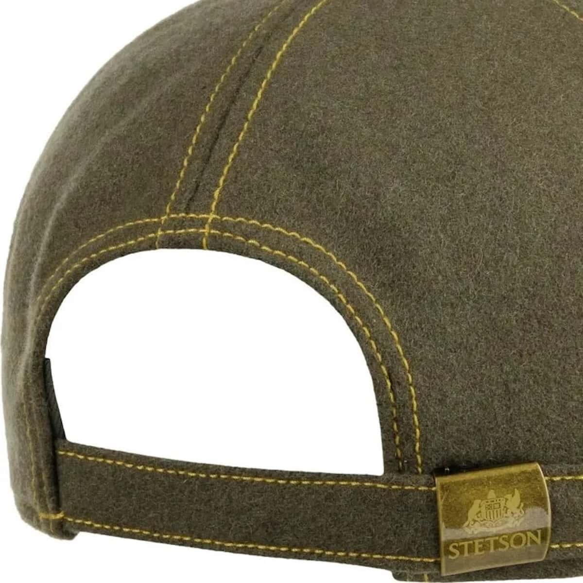 Close-up of the back of a Stetson cap in olive green wool felt with yellow contrast stitching and a gold-tone metal brand patch on the strap.