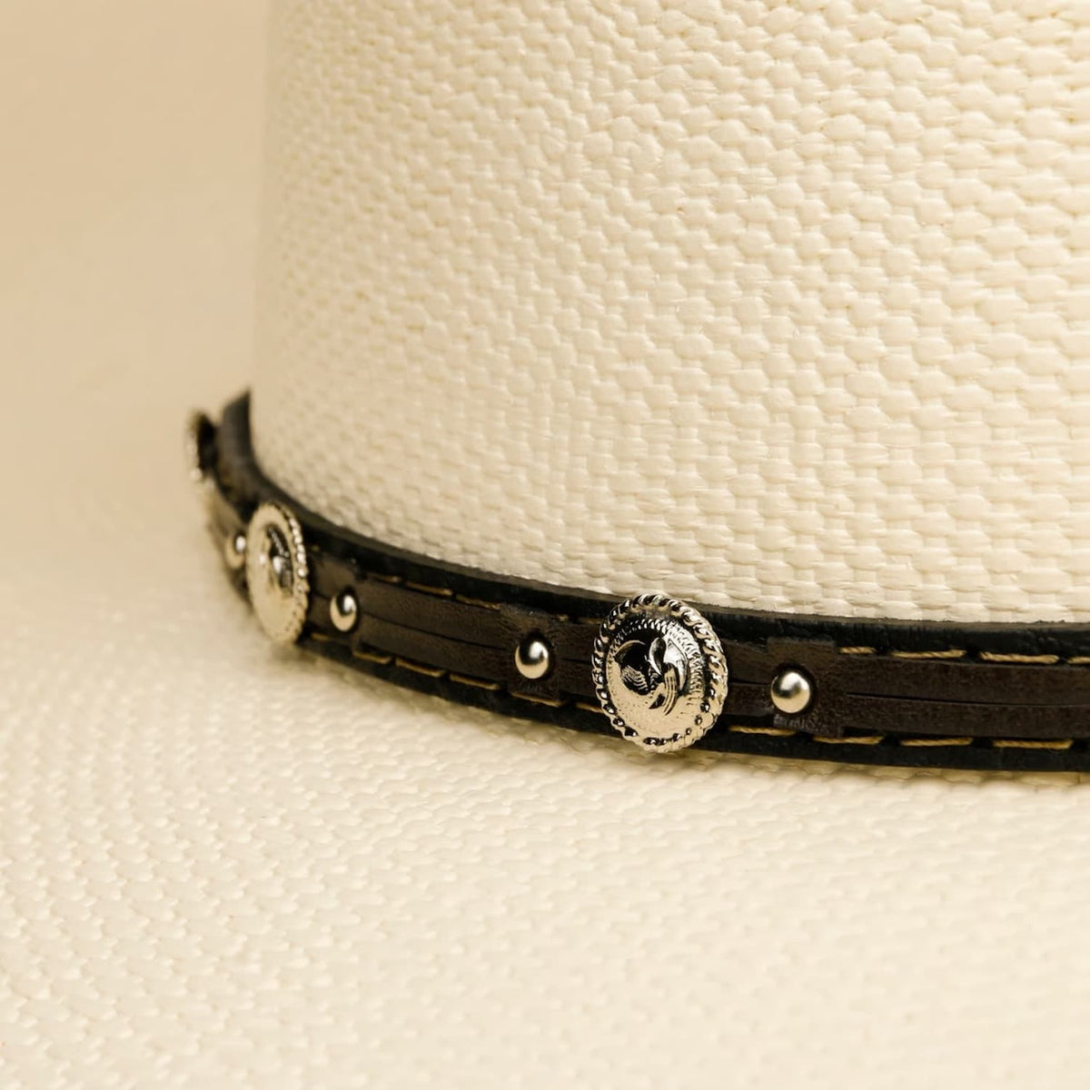 Close-up of a Stetson cowboy hat with a decorative band featuring metal studs and a central emblem.