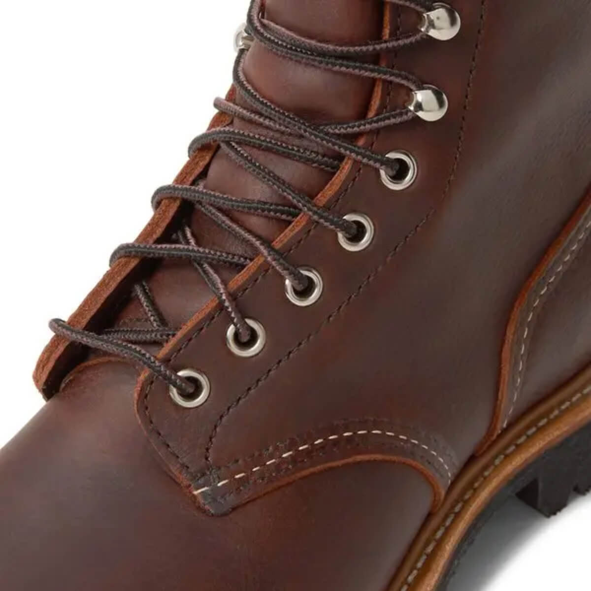 Close-up of a brown leather boot with laces on a white background
