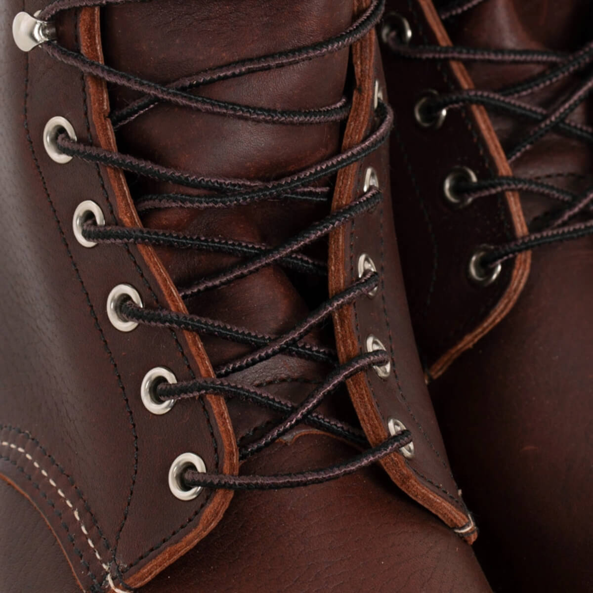 Close-up of brown leather boots with black laces and metal eyelets.