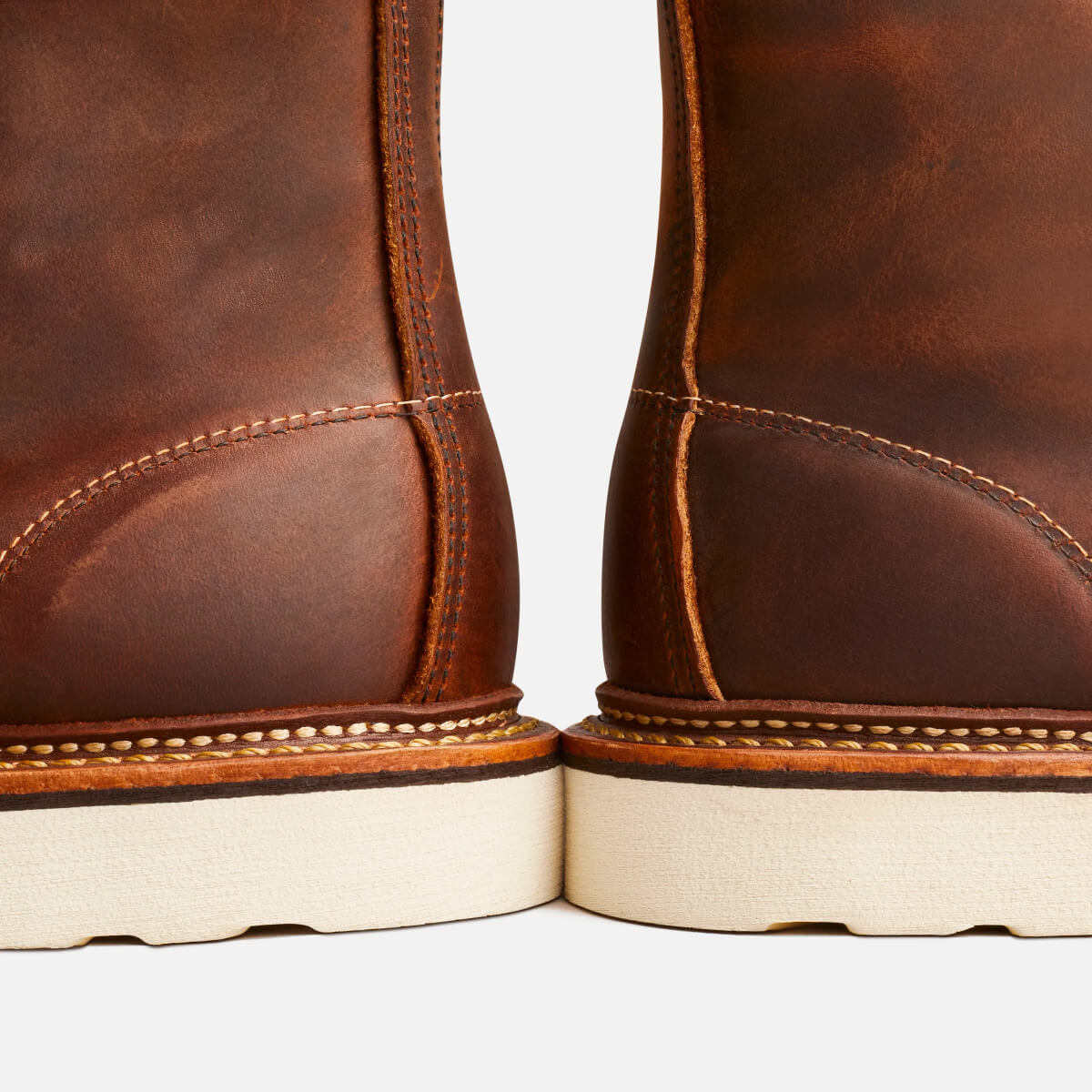 Close-up of brown leather boots with white soles on a white background