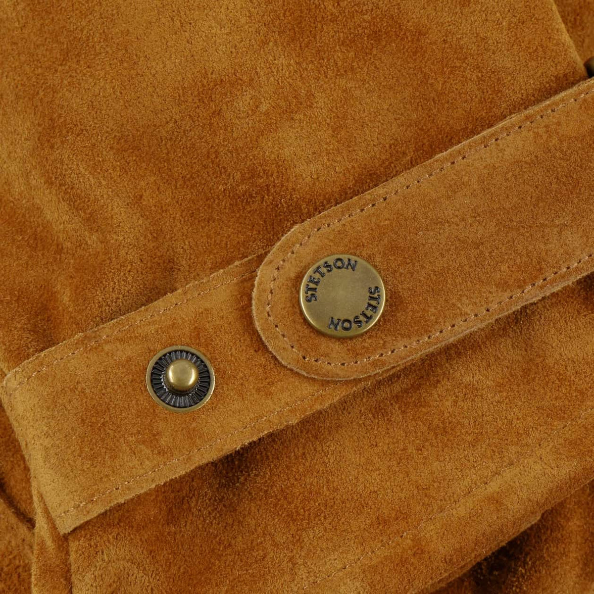 Close-up of Stetson Revetal Leather Gloves with a stitched strap and two metal snap buttons. One round button is gold-toned and the other is blue-toned, both with a circular Stetson logo.