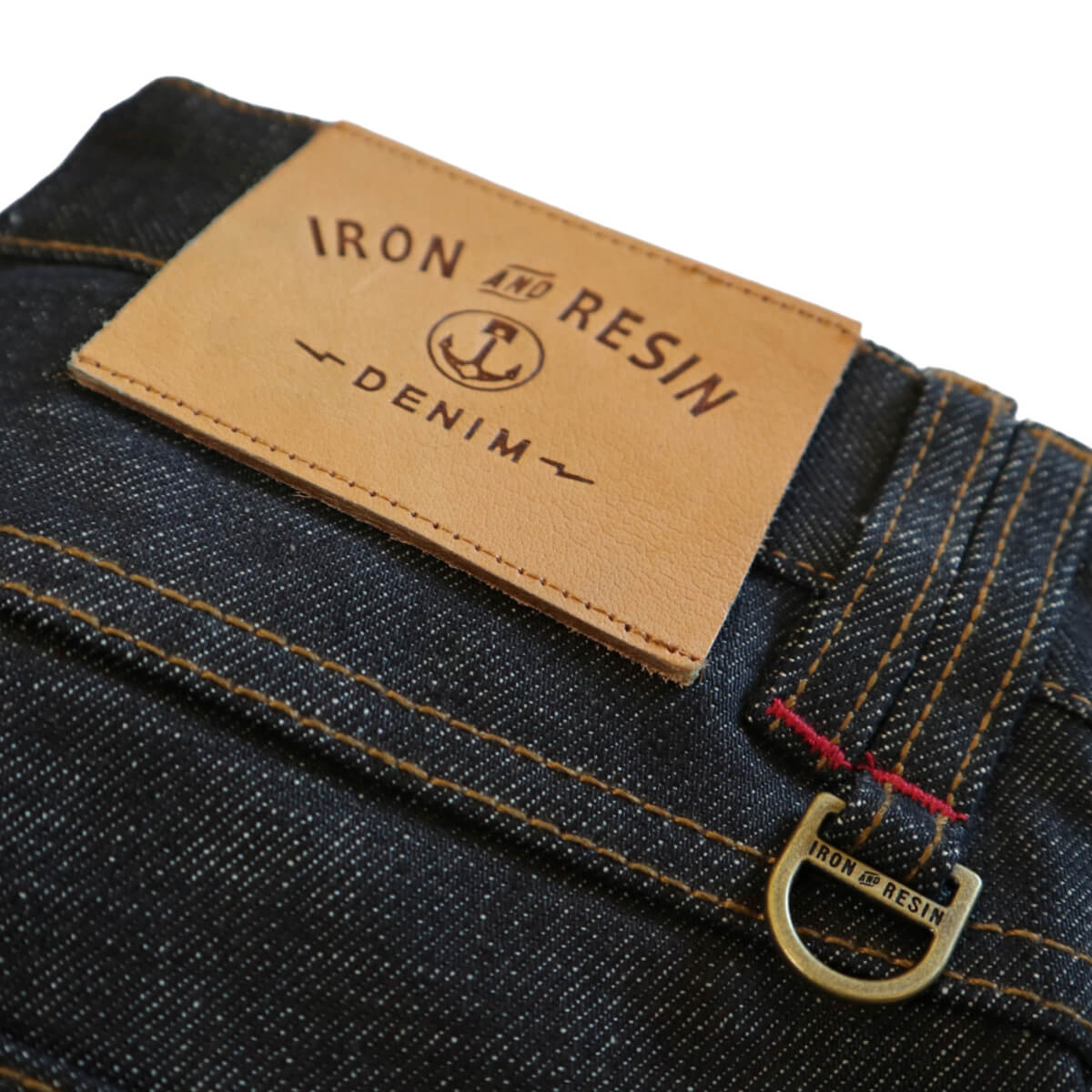 Close-up of a denim label with &#39;Iron and Resin&#39; branding on a white background
