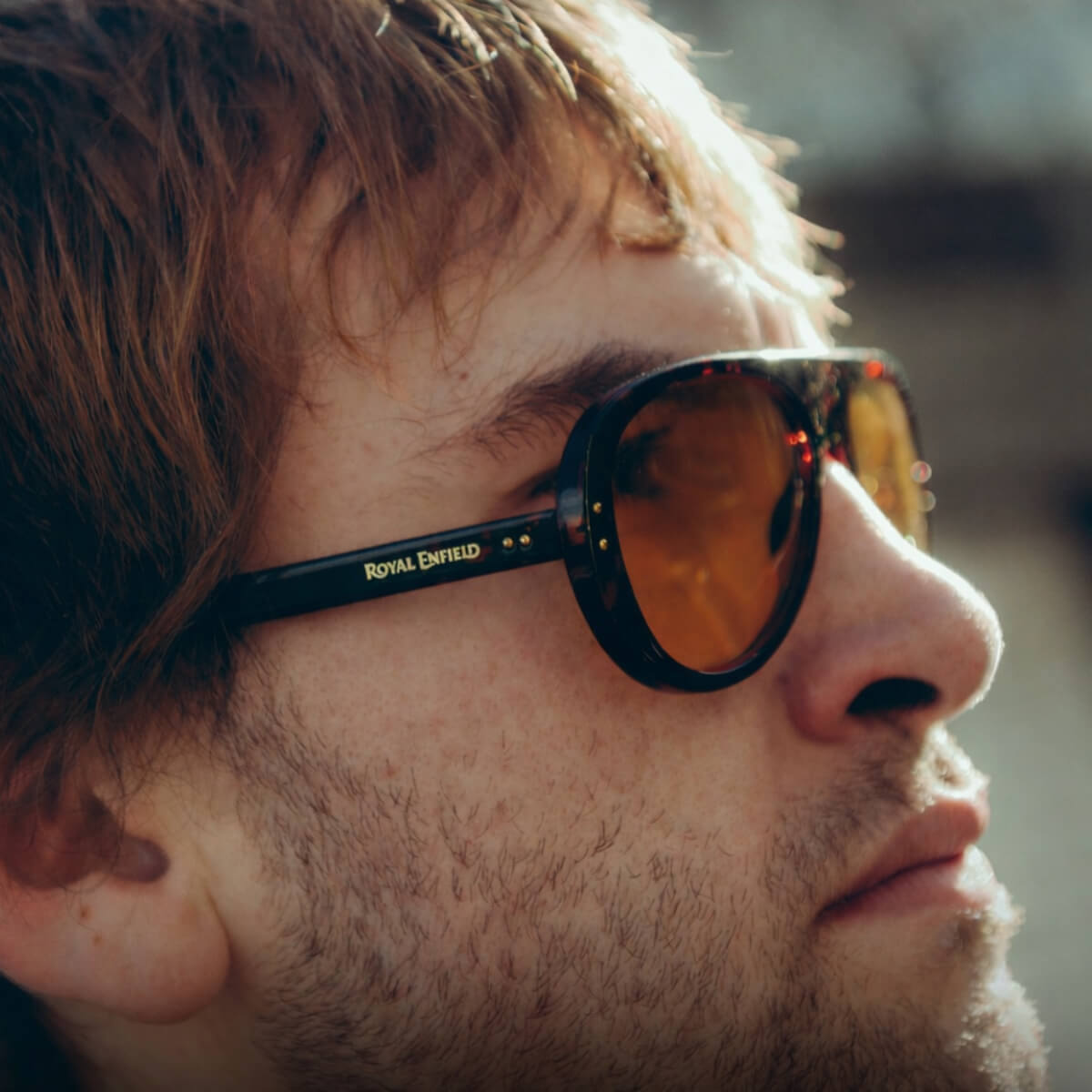 Close-up of a person wearing sunglasses with 'Royal Enfield' branding.