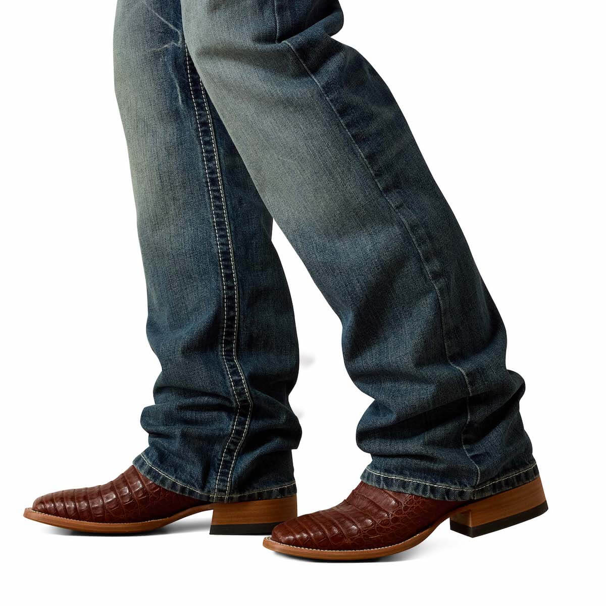 Blue jeans worn with brown leather boots on a white background