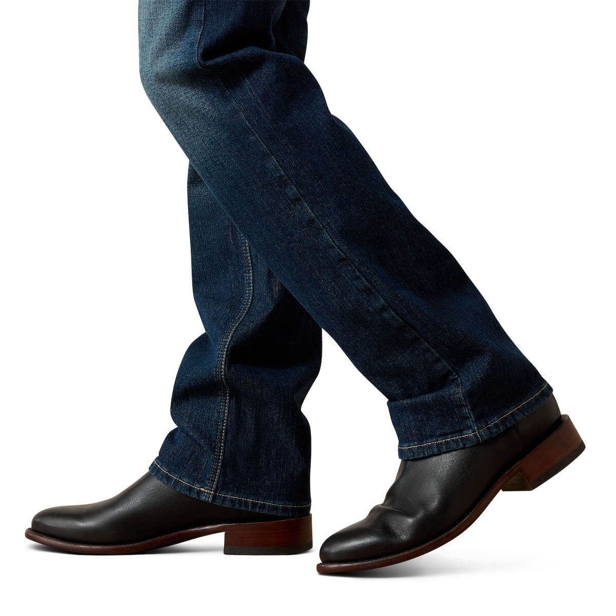 Black leather shoes worn with blue jeans on a white background