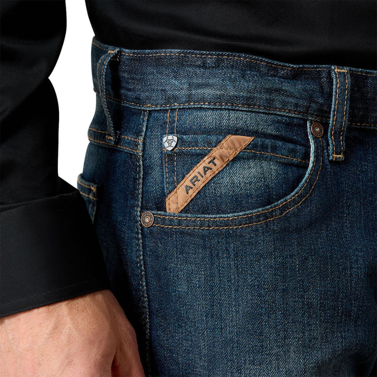 Close-up of blue jeans with Ariat logo on the pocket against a white background