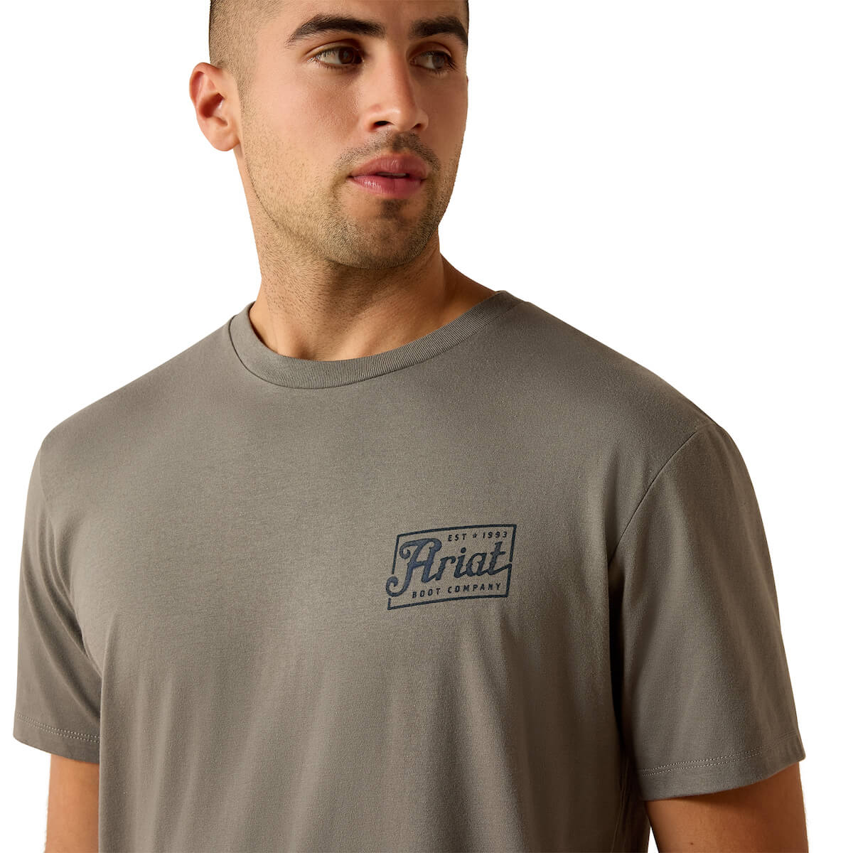 Man wearing a grey t-shirt with the Ariat logo on a white background