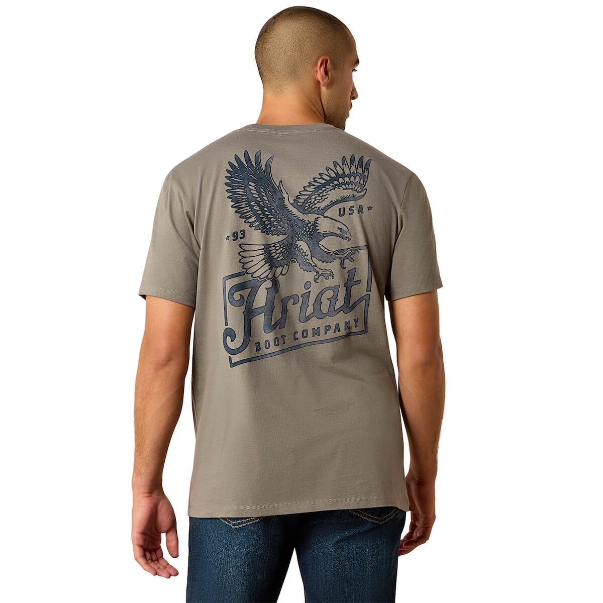 Man wearing a beige t-shirt with an eagle and 'Ariat' logo on a white background