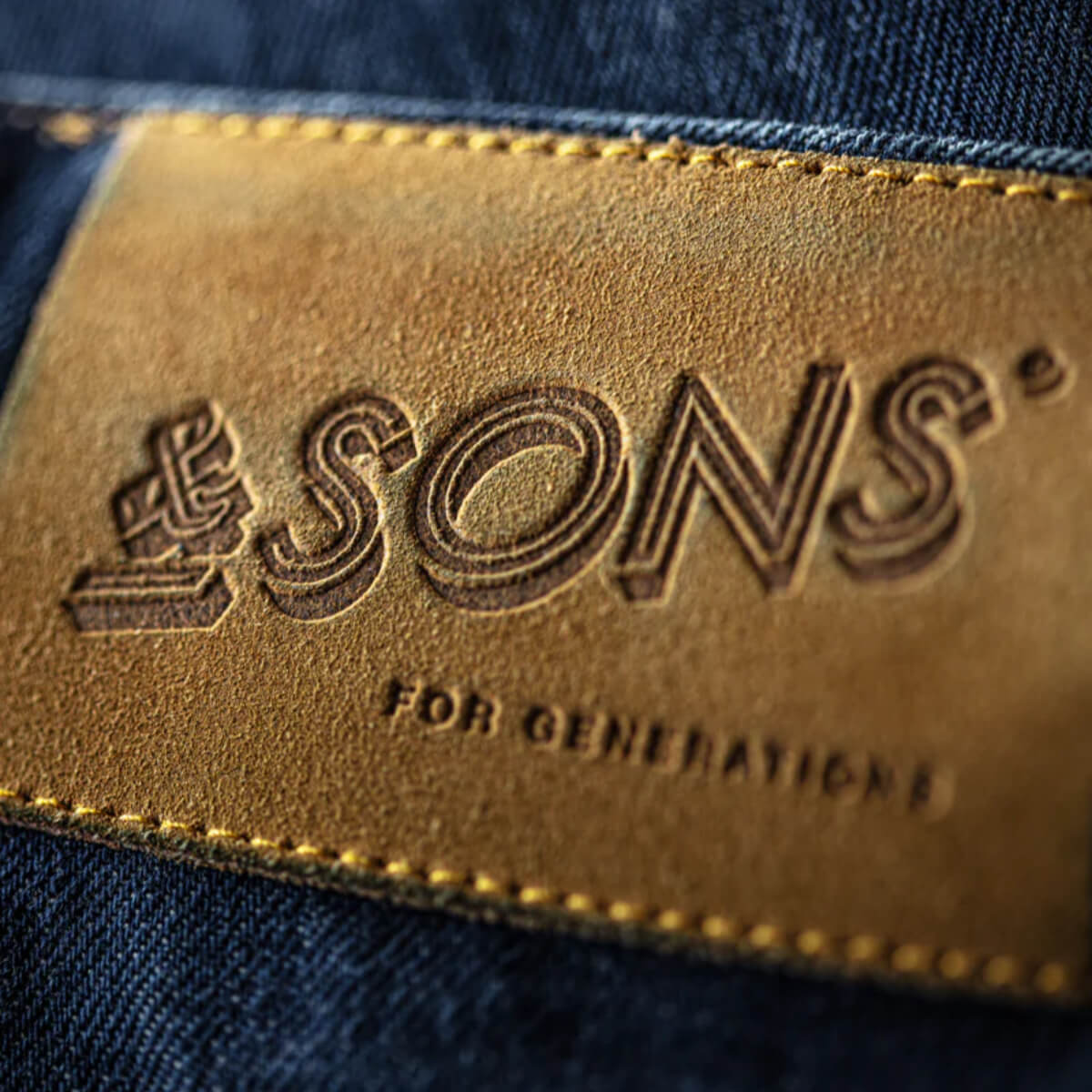 Leather label with 'SONS' branding on denim fabric