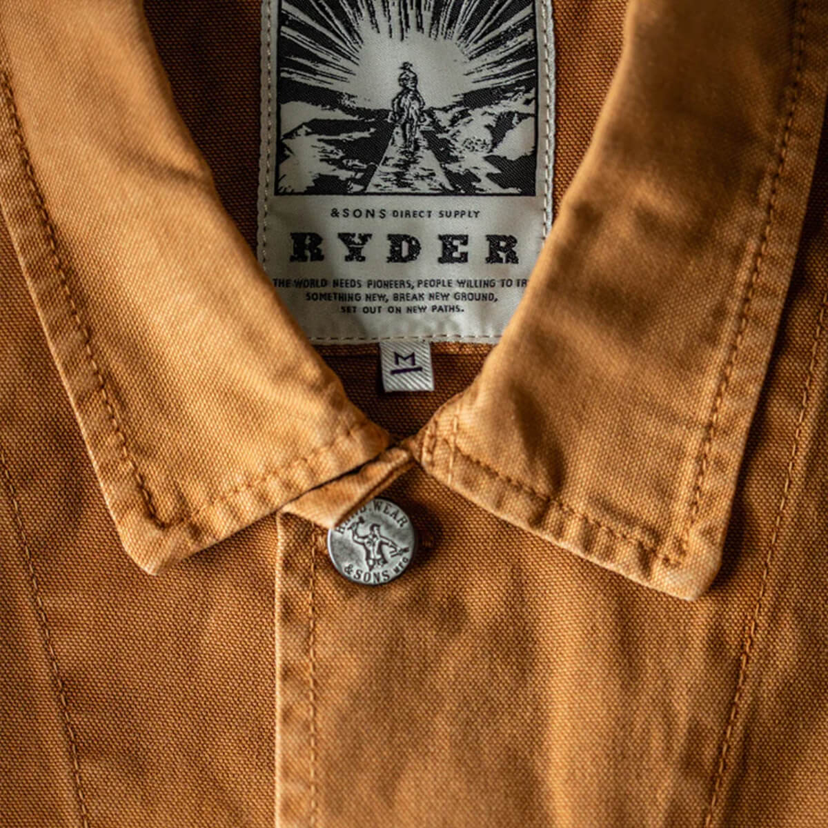 Close-up of a brown jacket with a &#39;Ryder&#39; label and button.