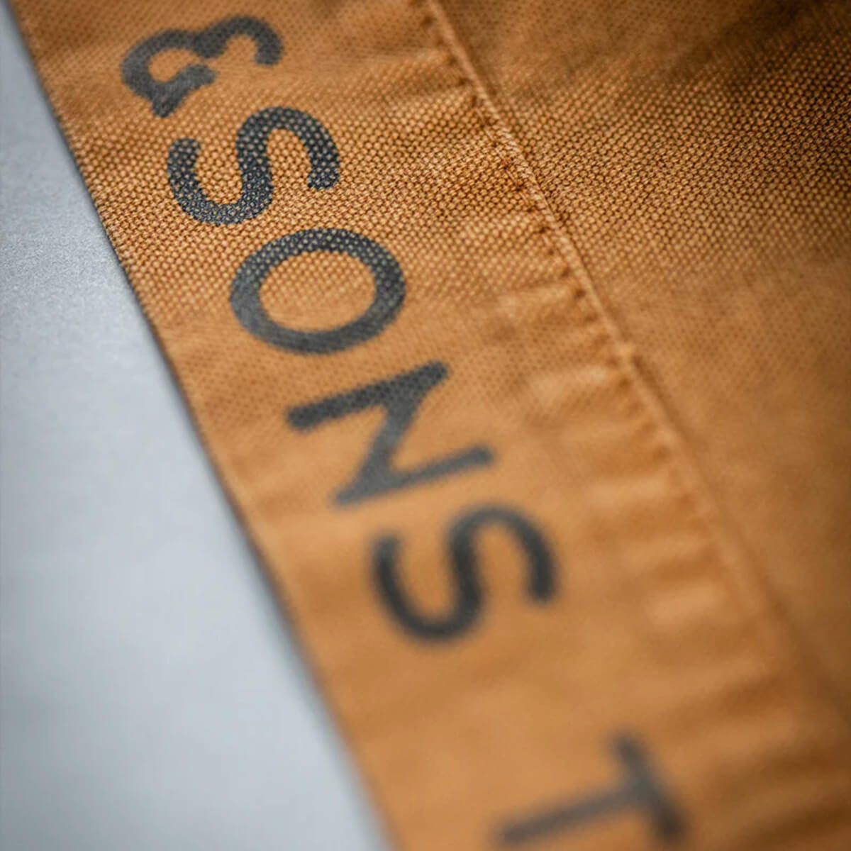 Close-up of a fabric label with &#39;SONS&#39; printed on it.
