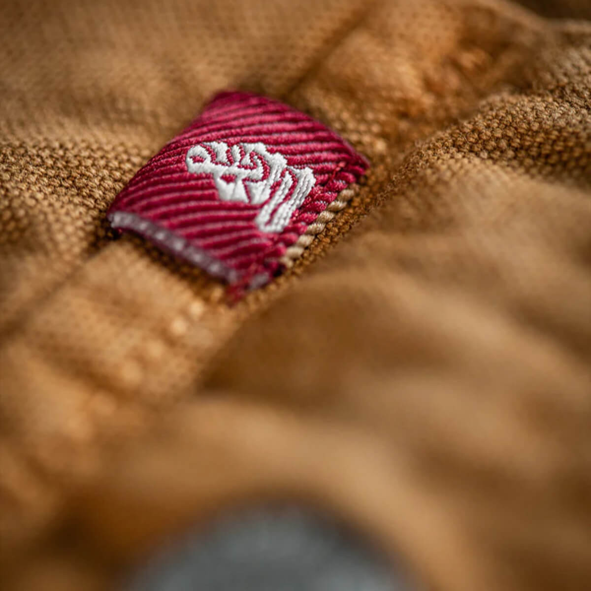 Close-up of a red and white logo on a textured brown fabric surface