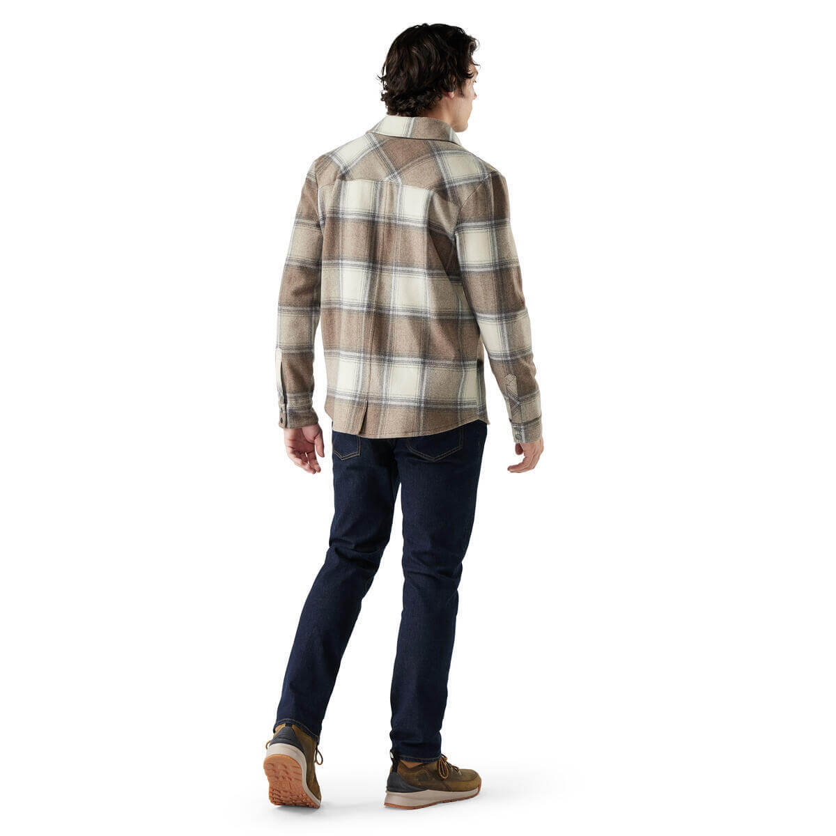 Man wearing a plaid shirt and dark pants on a white background