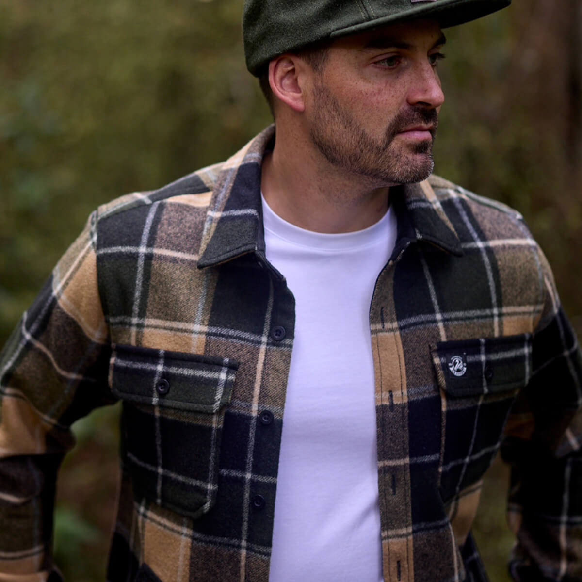 Man wearing a plaid shirt and cap outdoors