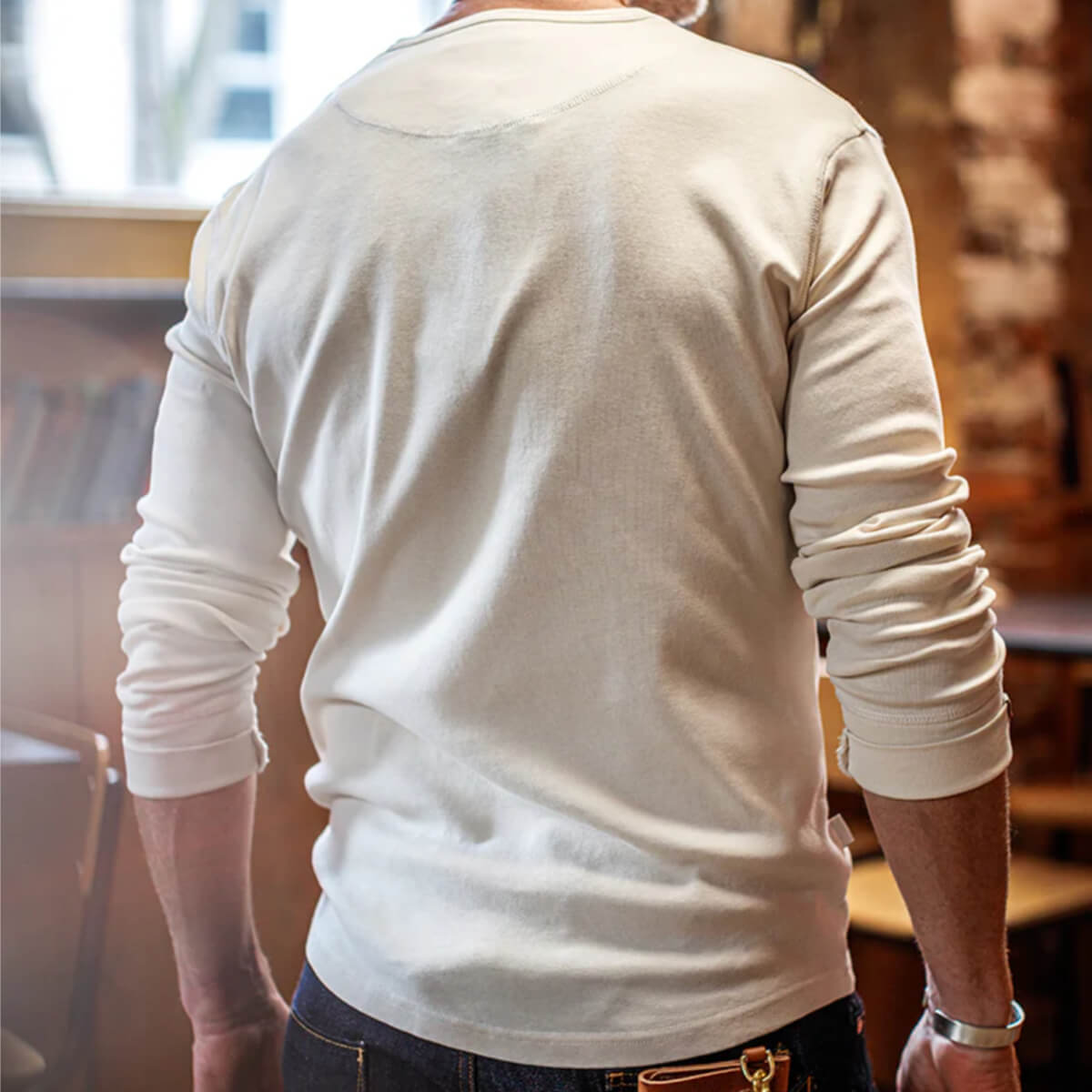 Person wearing a white long-sleeve shirt in an indoor setting