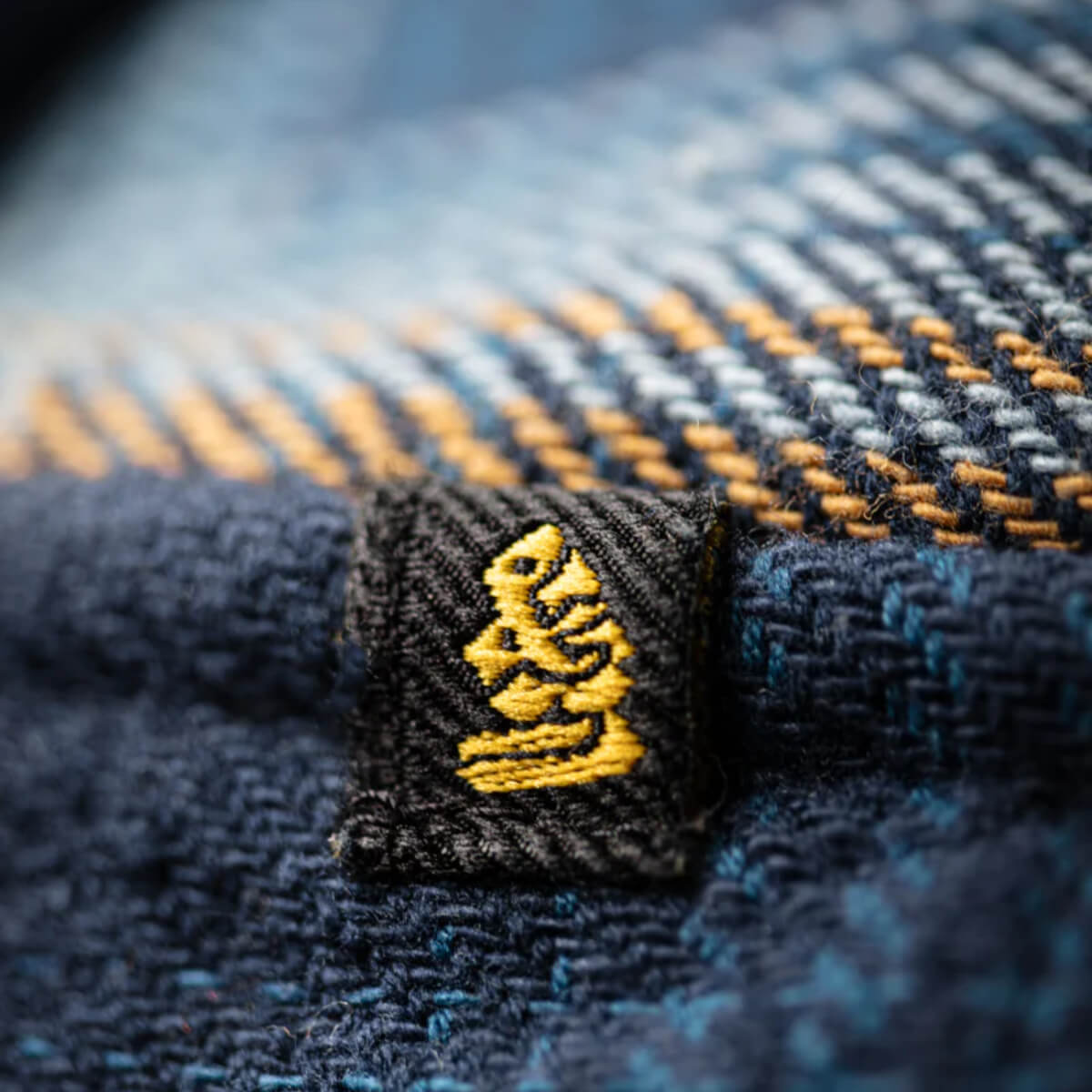 Close-up of a textured fabric with a yellow logo on a dark background