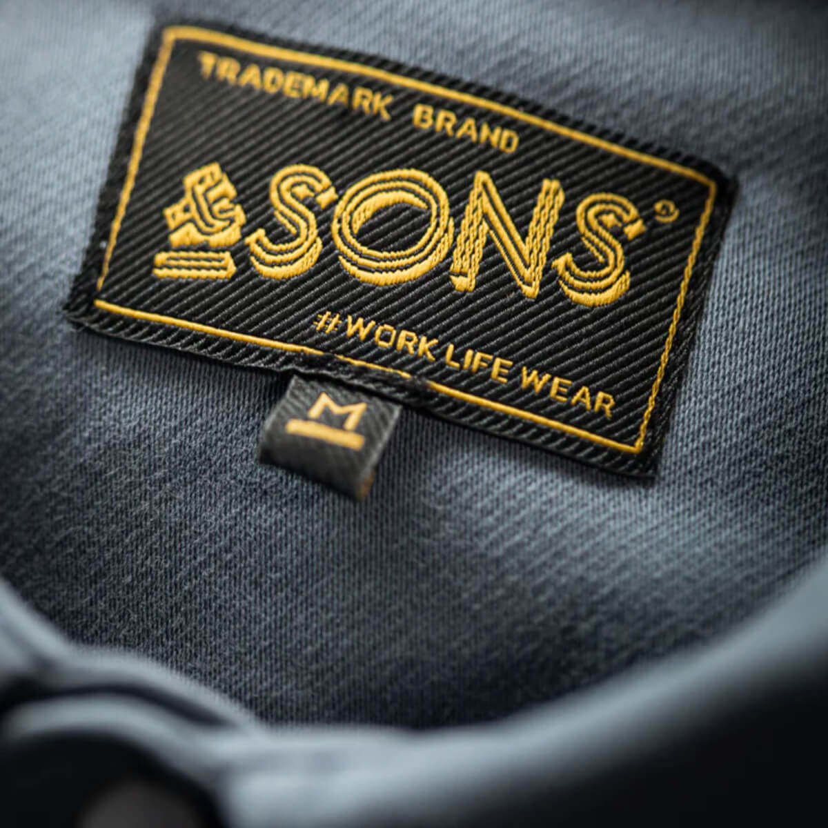 Close-up of a 'SONS' brand label on a dark fabric background