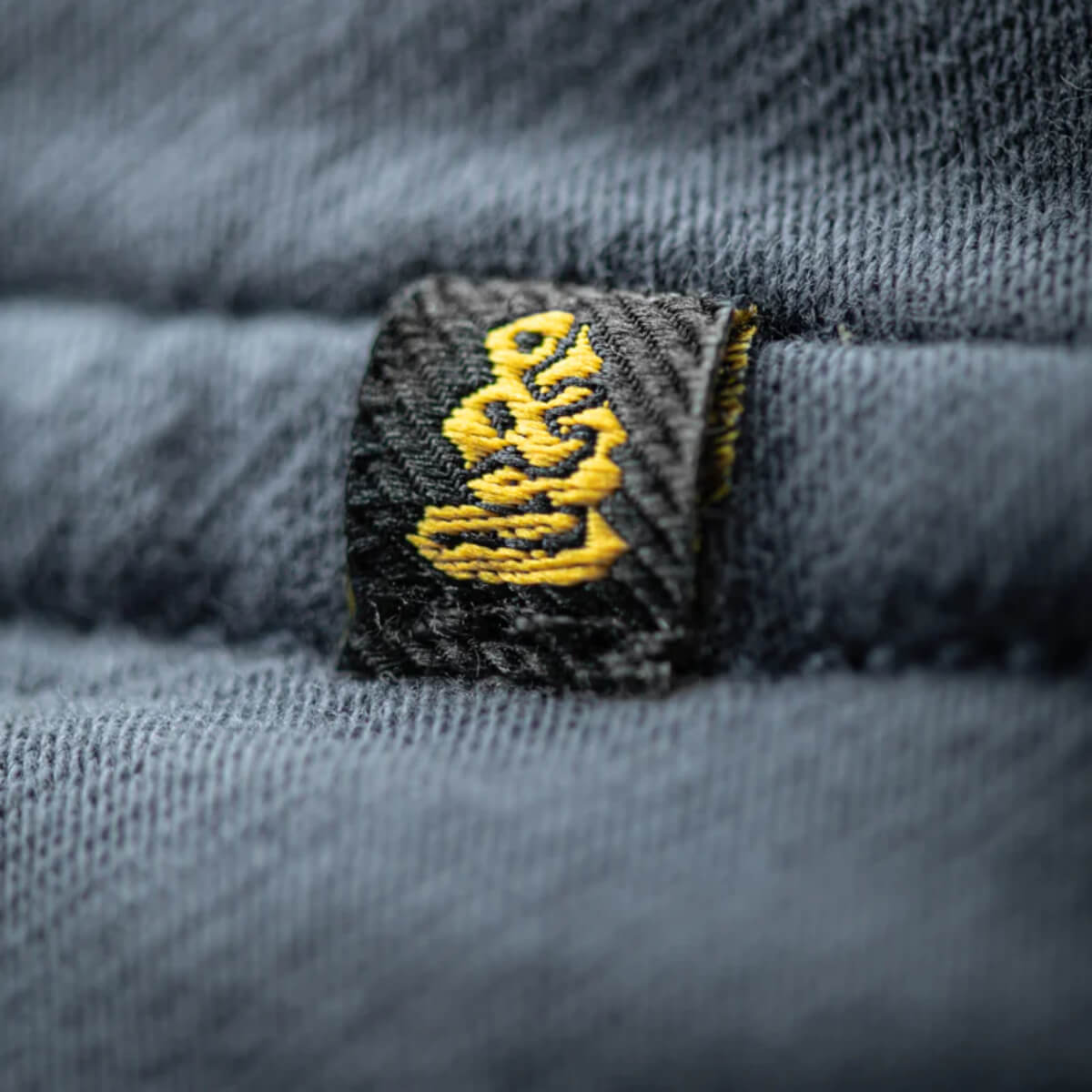 Close-up of a textured fabric with a yellow logo on a gray background