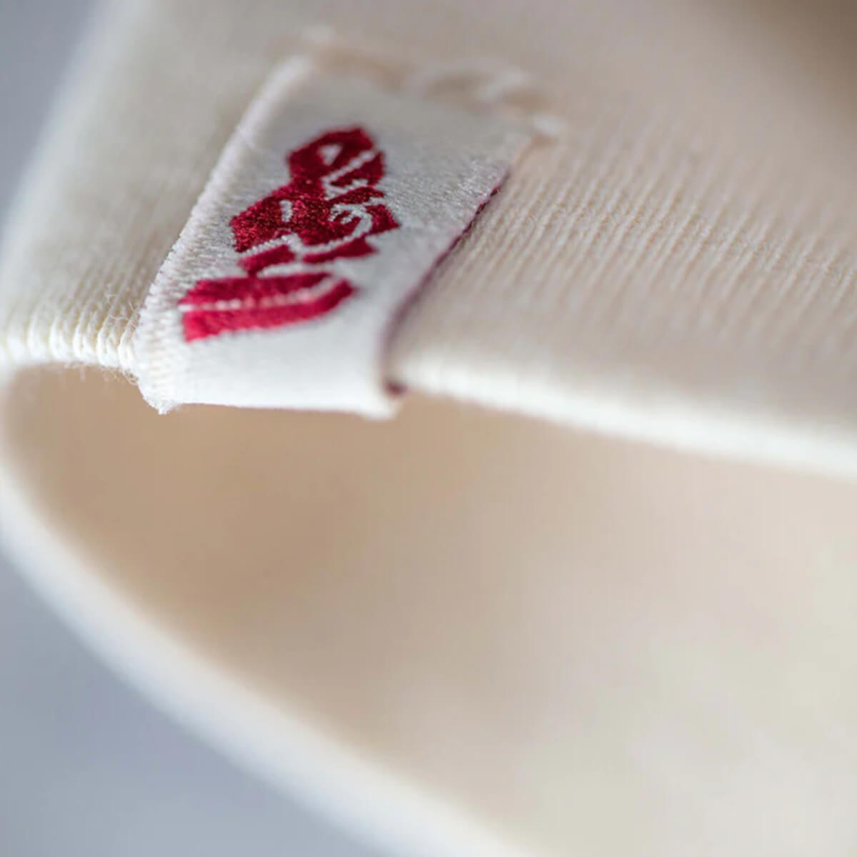 Close-up of a white sock with a red label on a light gray background
