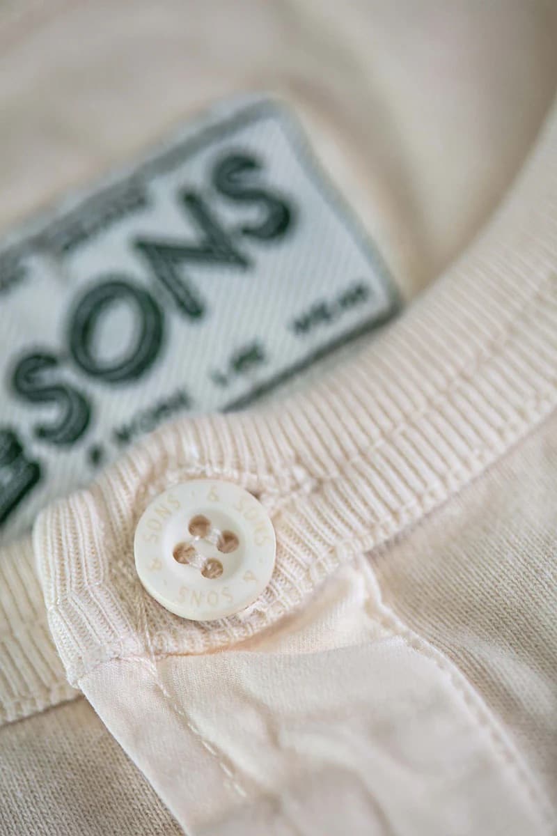 Close-up of a button on a garment with a brand label in the background.
