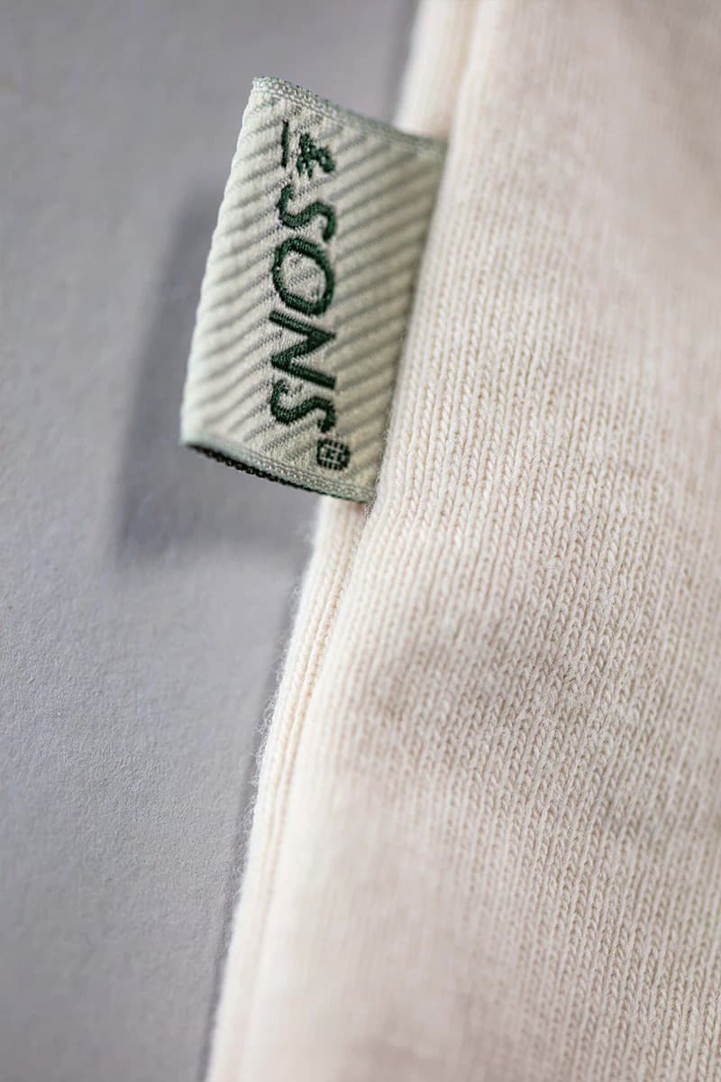 Close-up of a label on a beige garment with '&SONS' branding.