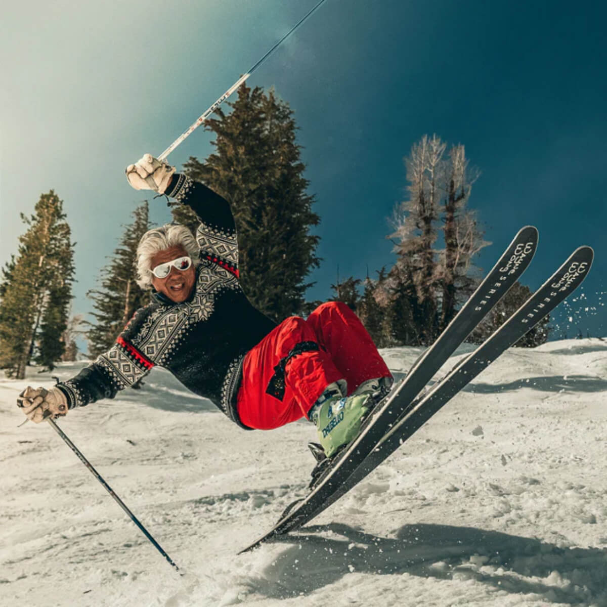 Wayne Wong skiing in a snowy landscape with trees and clear sky