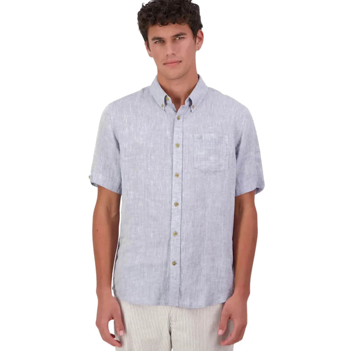 A man wearing a light grey Swanndri short-sleeve button-down shirt with a chest pocket, paired with light beige pants, against a plain white background.