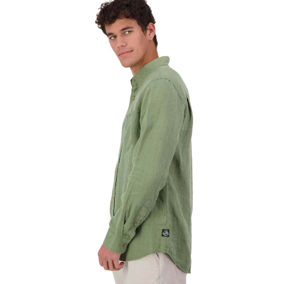 A man wearing a Swanndri sage green long-sleeve linen button-down shirt, shown from a side profile against a plain white background.