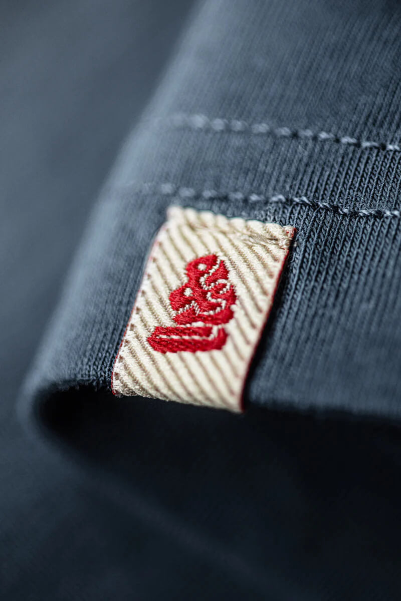 Close-up of a navy blue fabric with a red logo on a beige label.