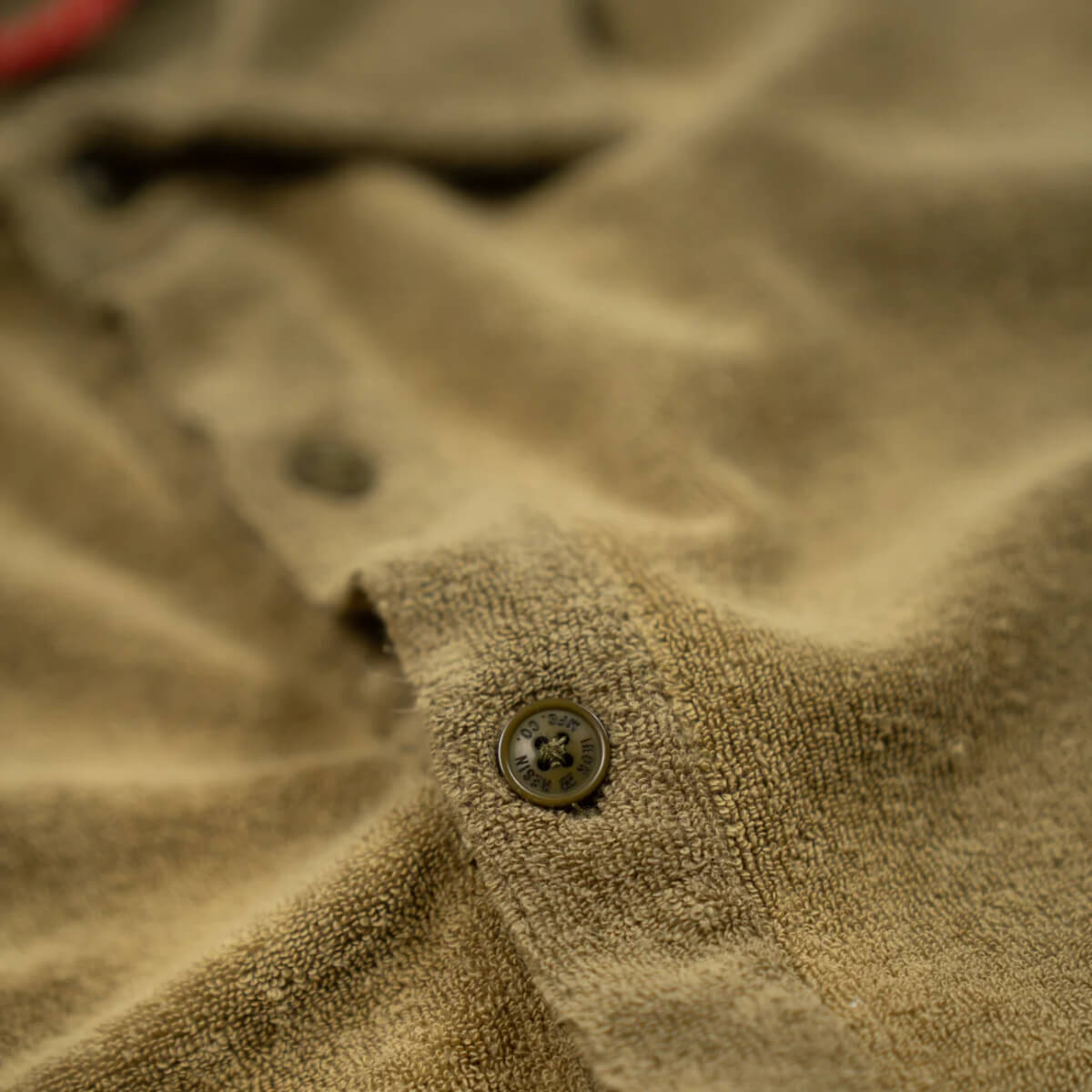 Close-up of a textured beige fabric with a button
