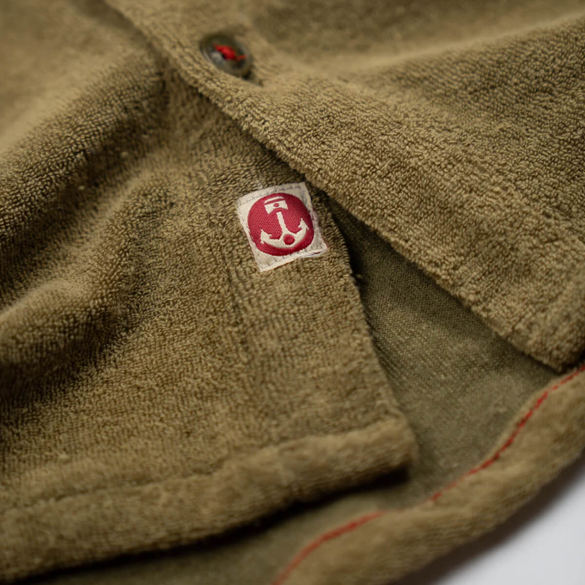 Close-up of a textured fabric with a red and white logo on a brown background