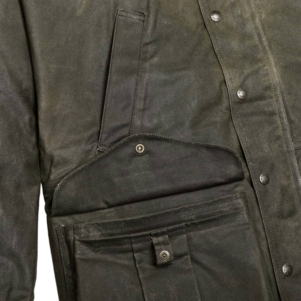 Close-up of a Filson Tin Cloth Field Jacket showing the fabric texture, metal snap buttons, and a front utility pocket.