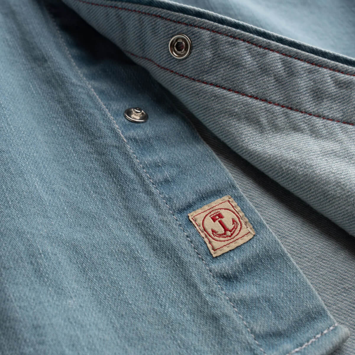 Close-up of a blue denim jacket with a brand logo on the chest pocket.