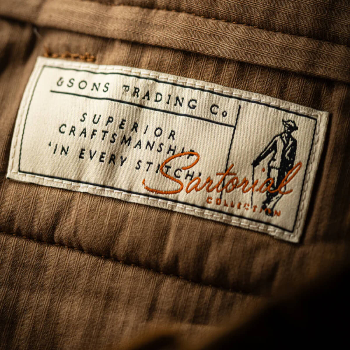 Label on a brown fabric with &Sons Trading Co.' text and 'Sartorial Collection' branding.