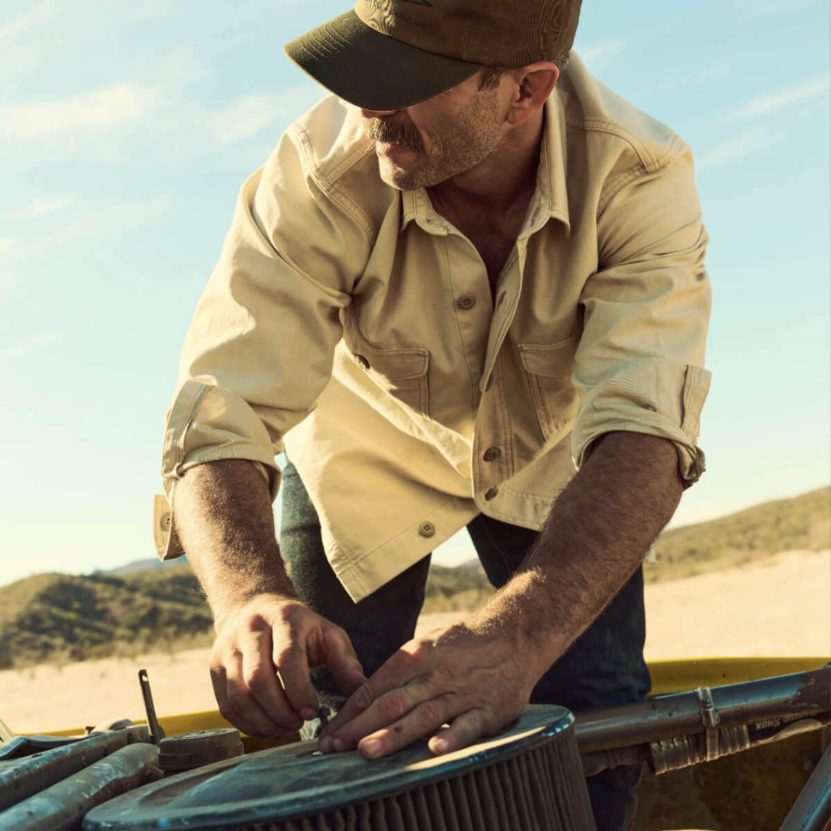 Man working on a vehicle in a desert setting