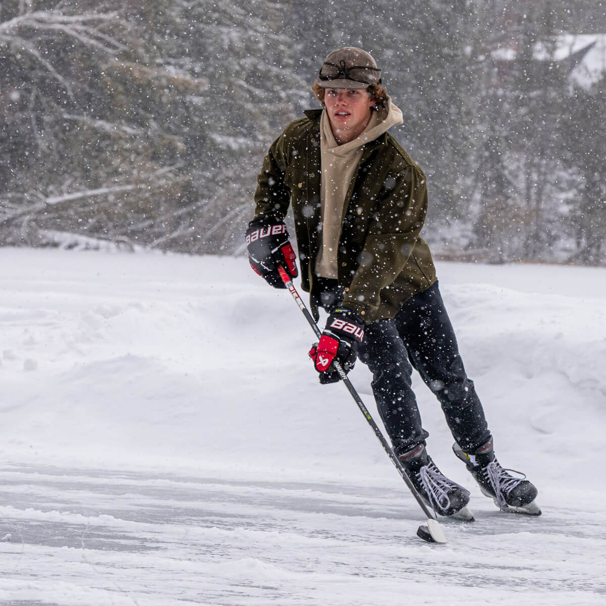 Person ice skating on a frozen lake during a snowstorm
