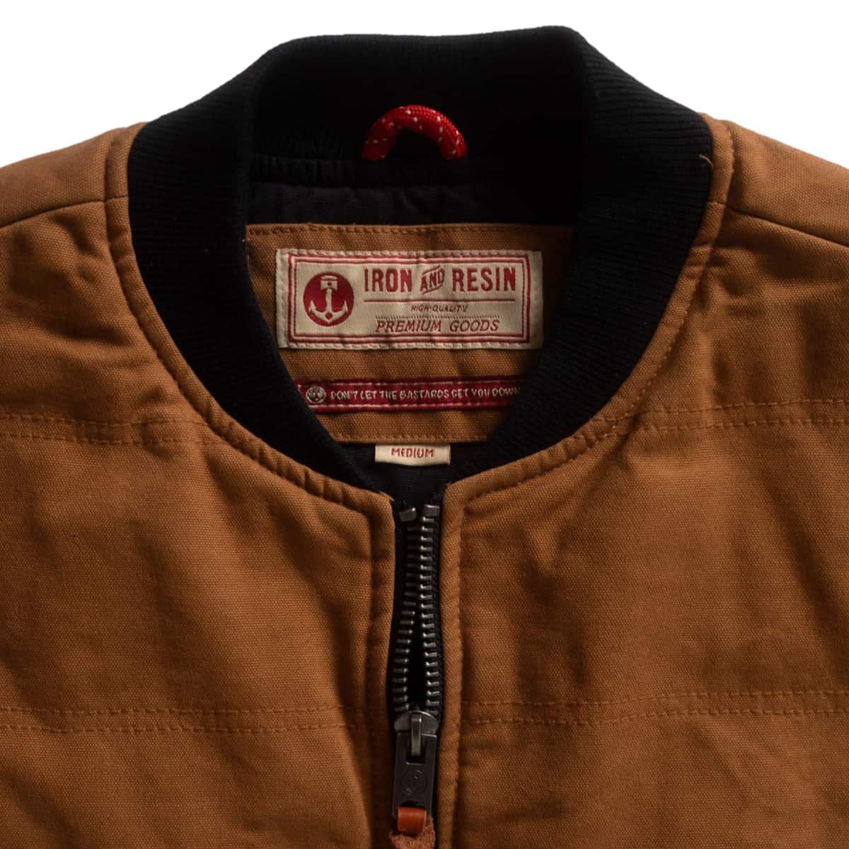 Close-up of a brown vest with a black ribbed collar and a visible Iron Resin brand label inside the neck.