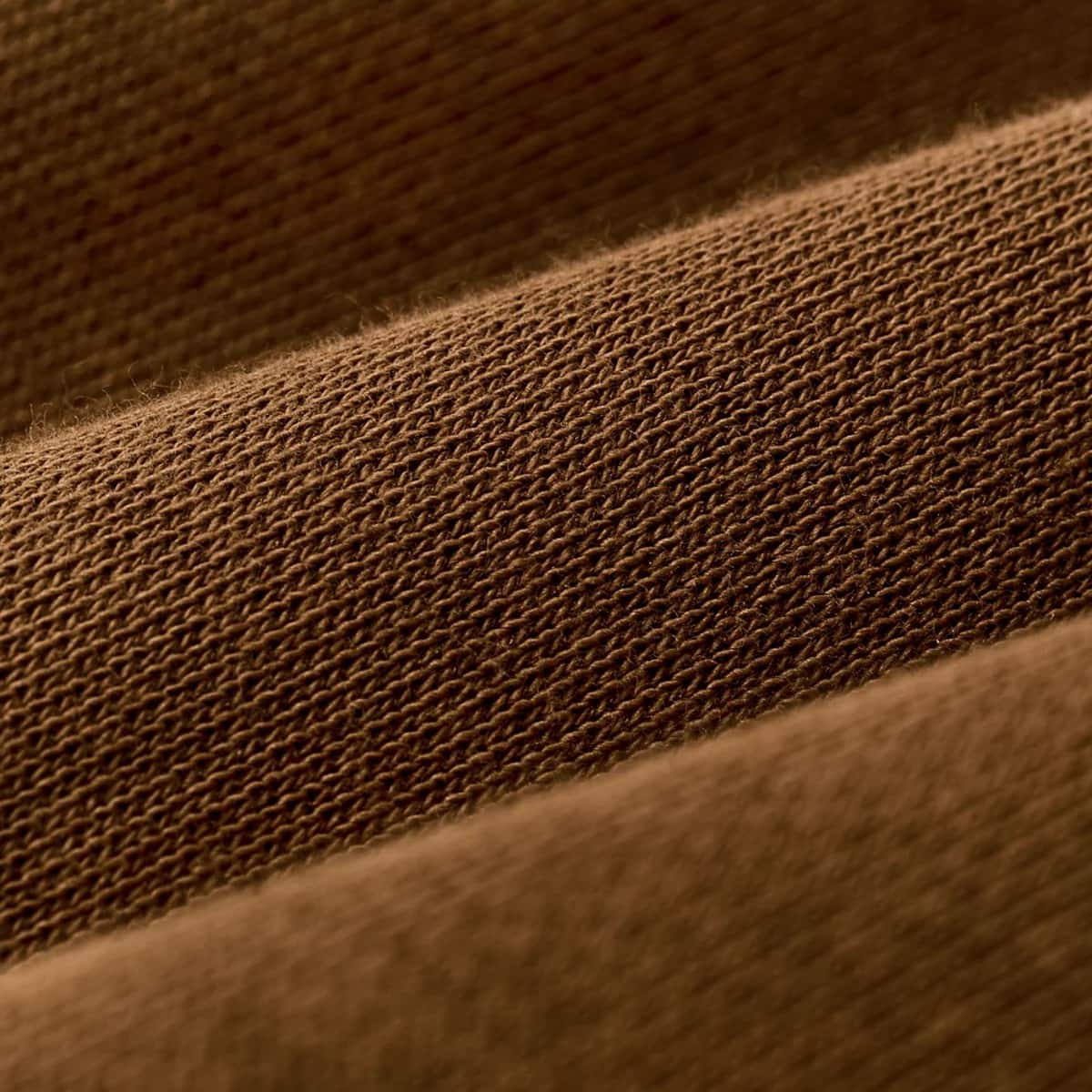 A close-up of a brown textured Filson fabric with a fine woven mesh or knit pattern, shown in soft diagonal folds.