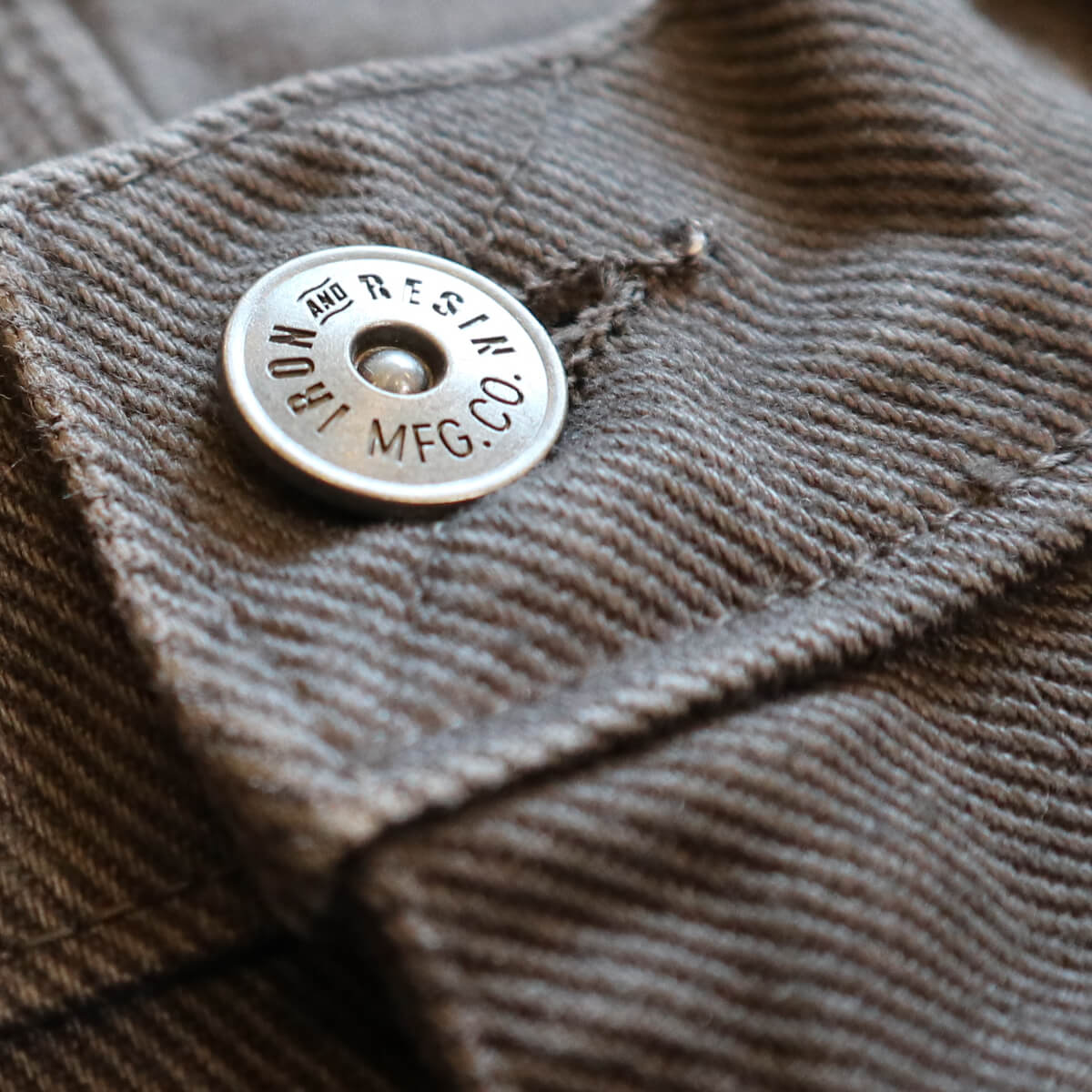 Close-up of a textured fabric surface with a metal button featuring text.