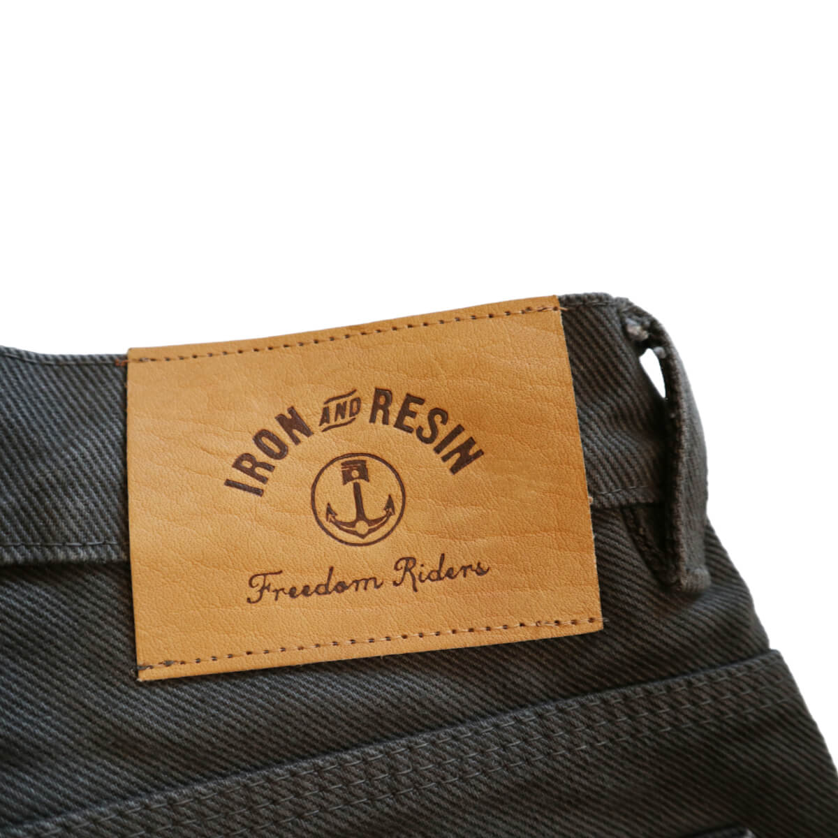 Close-up of a denim label with &#39;Iron and Resin&#39; branding on a white background