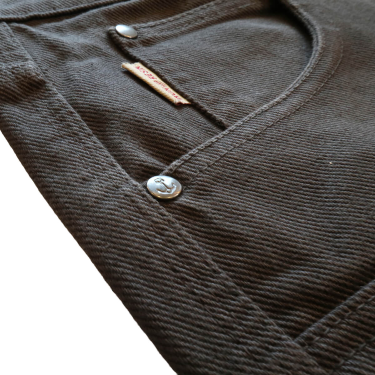 Close-up of a twill pants with buttons and a brand tag.